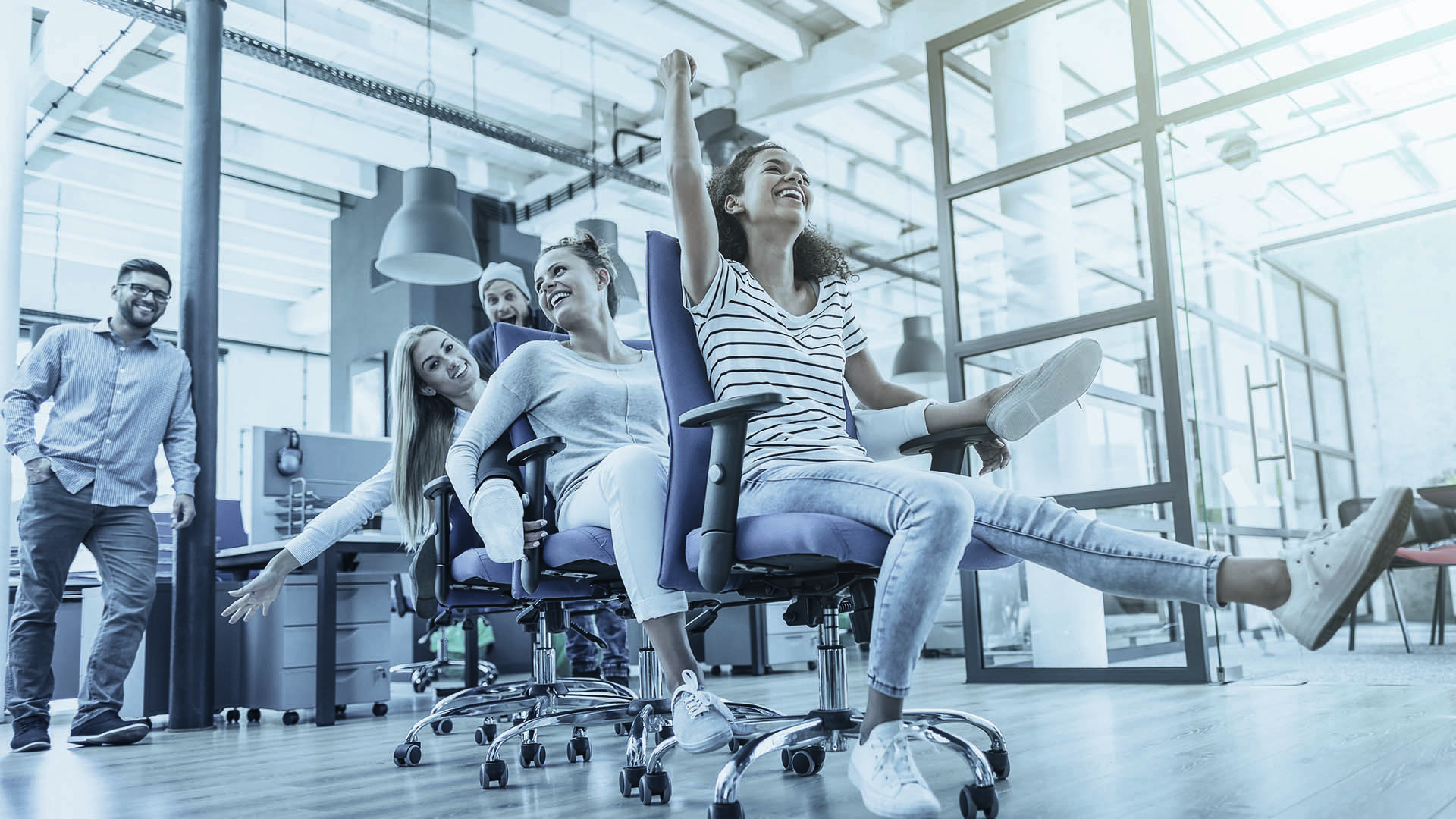 People in an office playing around with their office chairs