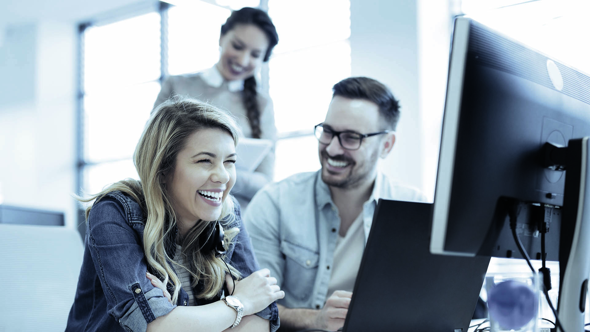 People sitting infront of a computer while smiling
